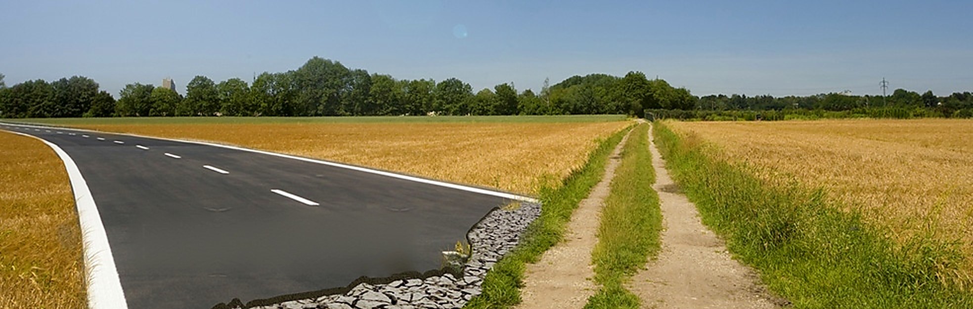 Neu gebaute Straße neben einem ausgefahrenen Feldweg, zwei Wege durch reife Kornfelder